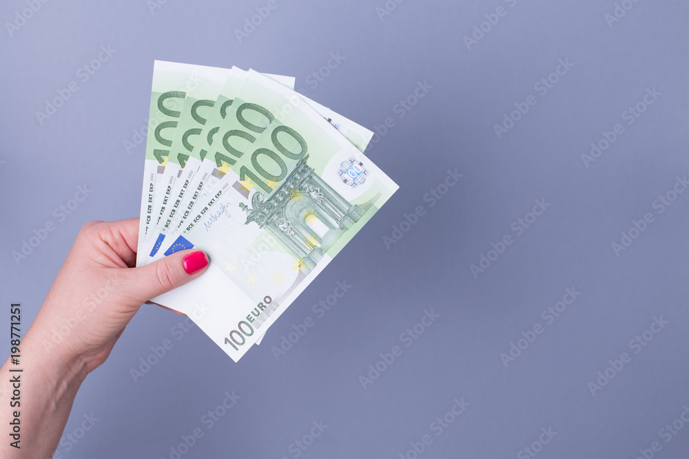 Female hand with a fan of euros on a blue background.Copy spase. Female hand with a fan of euros on a blue background.Copy spase.