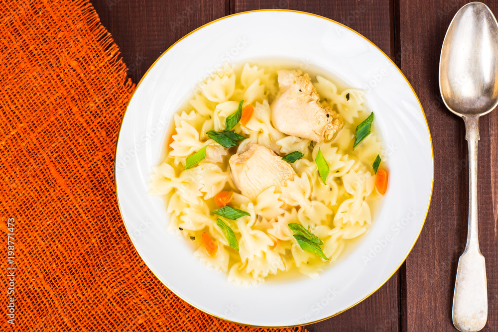 Chicken soup with farfalle in white plate