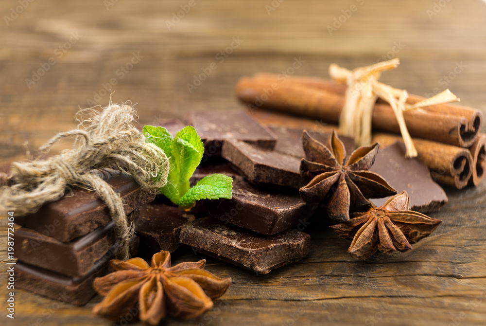 Pieces of chocolate, cinnamon and star anise on a wooden table. Pieces of chocolate, cinnamon and star anise on a wooden table.