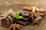 Pieces of chocolate, cinnamon and star anise on a wooden table.