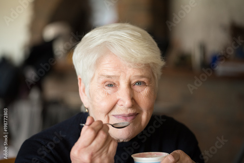 Older woman eats yogurt