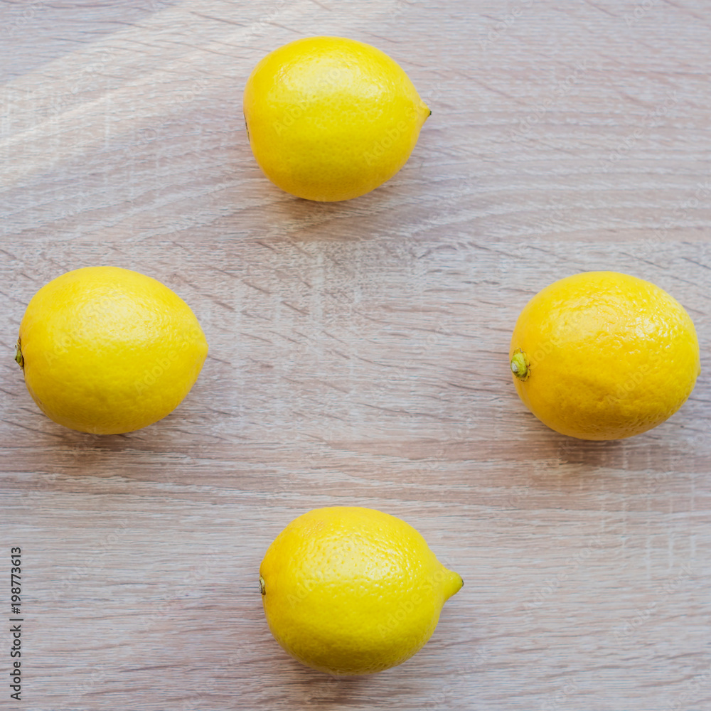 top view of four fresh lemons on wooden table, closeup