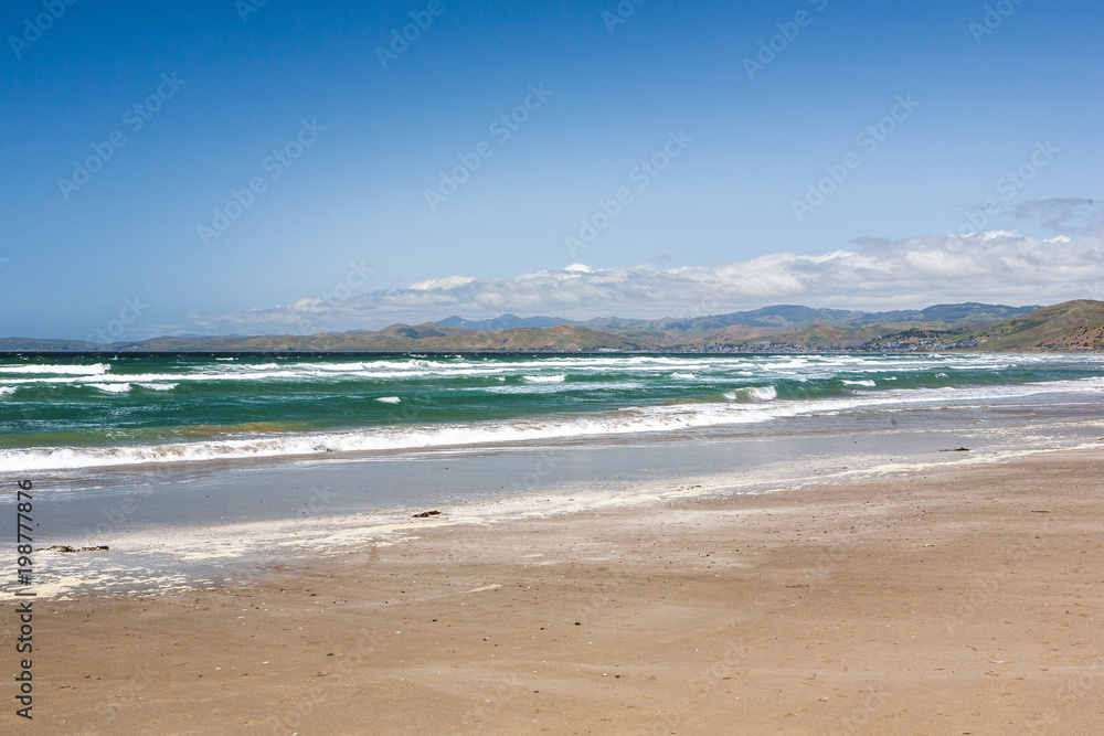 View of the Ocean Waves breaking on the sand in, in Morrow Bay, California