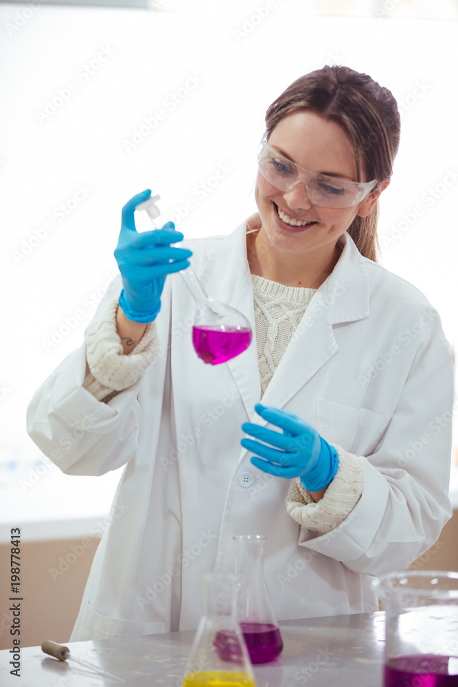 young woman scientist working with laboratory glassware with different colors liquid in a laboratory young woman scientist working with laboratory glassware with different colors liquid in a laboratory
