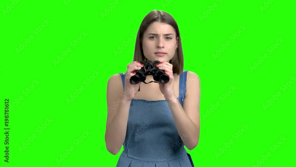 Portrait of a young woman looking through binoculars. Green screen hromakey background for keying. Portrait of a young woman looking through binoculars. Green screen hromakey background for keying.