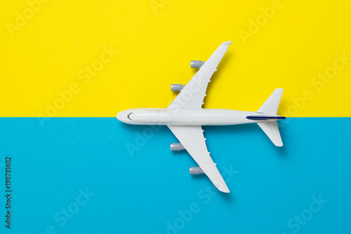 Miniature airplane model on blue and yellow background for travel theme