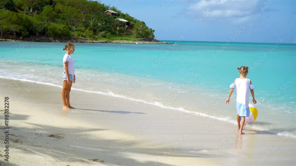 Little adorable girls playing with air ball on the beach. Happy kids enjoy vacation Little adorable girls playing with air ball on the beach. Happy kids enjoy vacation