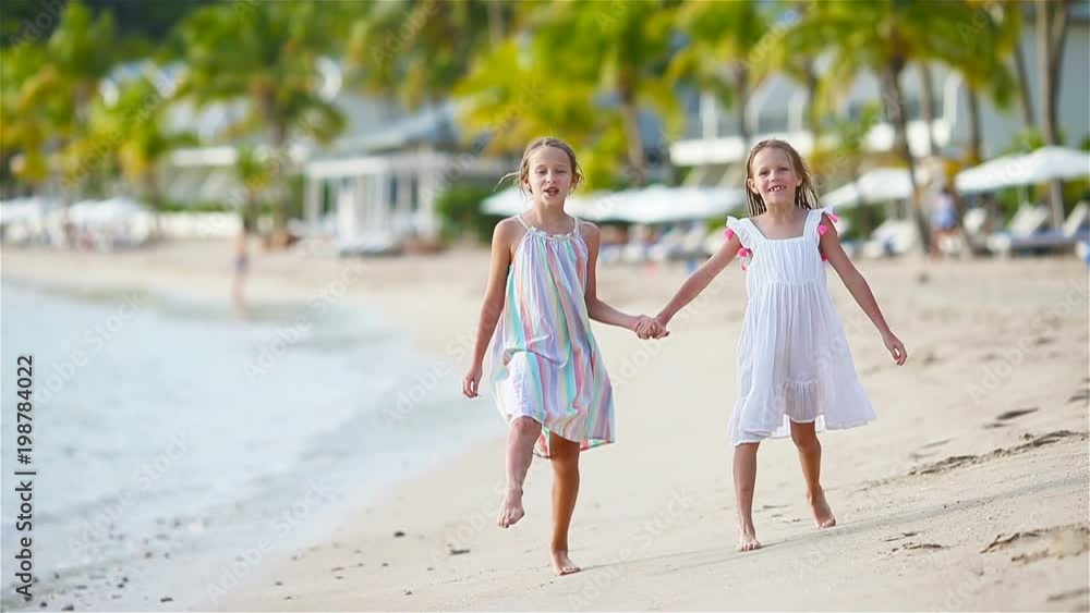 Little girls having fun at tropical beach during summer vacation playing together Little girls having fun at tropical beach during summer vacation playing together