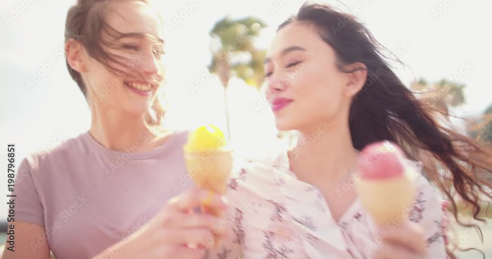 Female best friends walking and eating ice-cream on summer holidays Female best friends walking and eating ice-cream on summer holidays