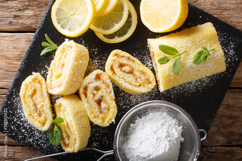 Traditional lemon roll with fruit curd, with mint and sugar powder close-up. Horizontal top view from above