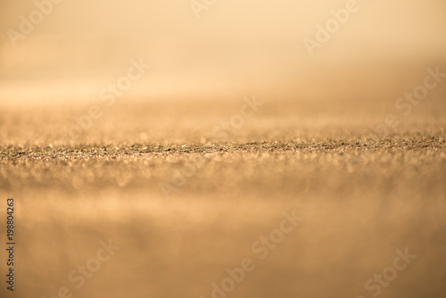 Blur tropical sunset beach with bokeh light sand abstract texture background.