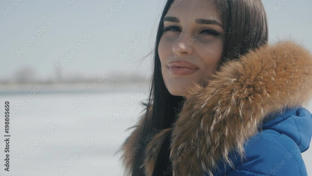 portrait of young beautiful brunette woman in winter on a snow background