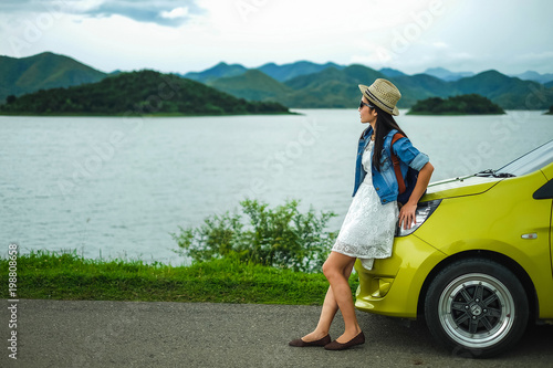 Woman traveler playing guitar near her car background is mountain.