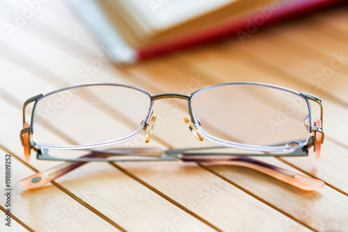 Glasses and open book on wooden table close