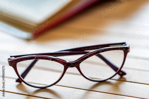 Glasses and open book on wooden table close