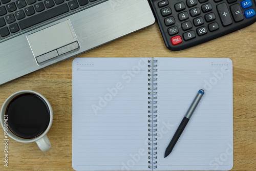 Laptop computer or notebook, calculator and cup of coffee on working table with copy space top view.