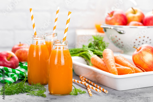 Fresh carrot and apple juice on white background. Carrot and apple juice in glass bottles on white table. Apple and carrot juice on white background