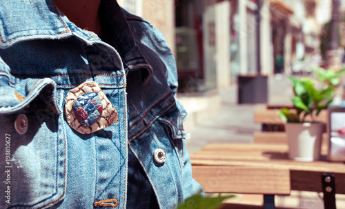 Part of denim woman fashion jacket. Handmade jewelry brooch of polymer clay. Urban background with blur street. Lifestyle trendy glamour card.