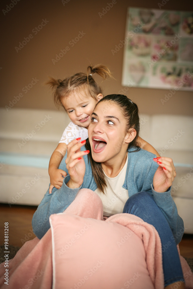  Cheerful mother and daughter playing on floor. Space for copy.