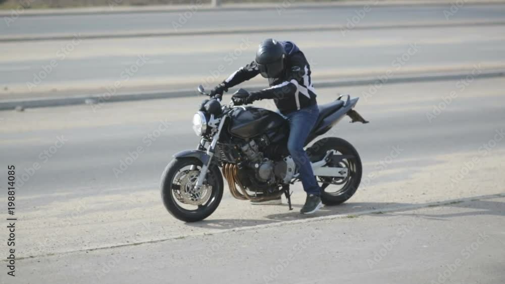 young attractive man motorcyclist with black helmet and sport motorcycle on street young attractive man motorcyclist with black helmet and sport motorcycle on street