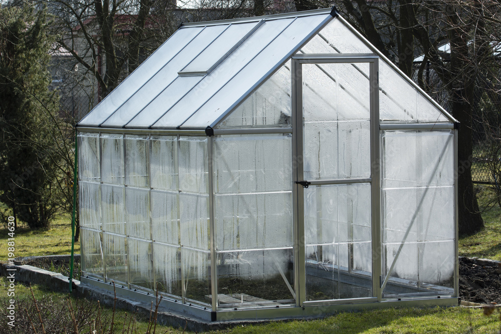 Plastic dewatered greenhouse in the garden. Plastic dewatered greenhouse in the garden.