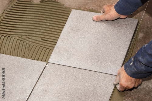 Hands of the worker lay ceramic granite on the floor. Close-up.