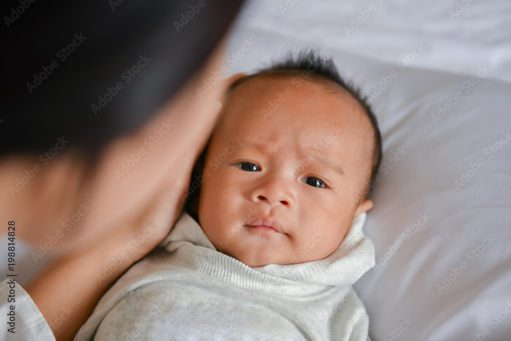 Newborn Concept. Mother and child on a white bed. Mom and baby boy playing in bedroom. Parent and little kid relaxing at home. Family having fun together. Newborn baby is fussing and crying. Newborn Concept. Mother and child on a white bed. Mom and baby boy playing in bedroom. Parent and little kid relaxing at home. Family having fun together. Newborn baby is fussing and crying.