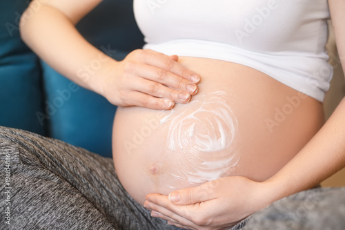 pregnant woman applying cream on her belly