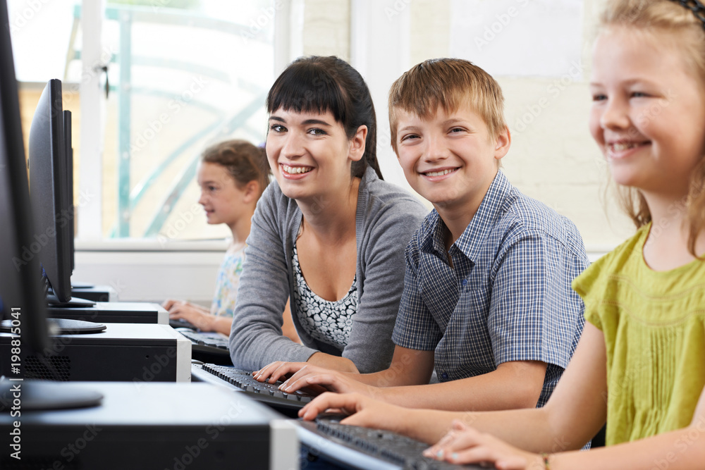 Portrait Of Male Elementary Pupil In Computer Class With Female Teacher Portrait Of Male Elementary Pupil In Computer Class With Female Teacher
