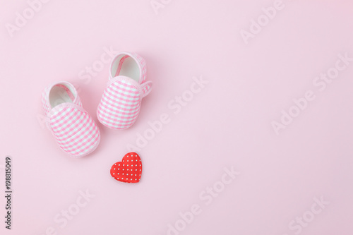 Table top view aerial image of decoration Happy mother’s day holiday background concept.Flat lay red heart & baby shoes on modern beautiful pink paper at home office desk.Design pastel tone and space.