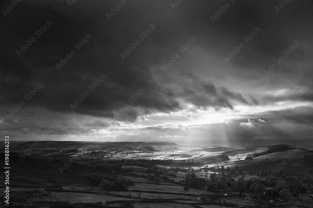 Black and white beautiful sunbeams over Big Moor in the Peak District landscape in Autumn