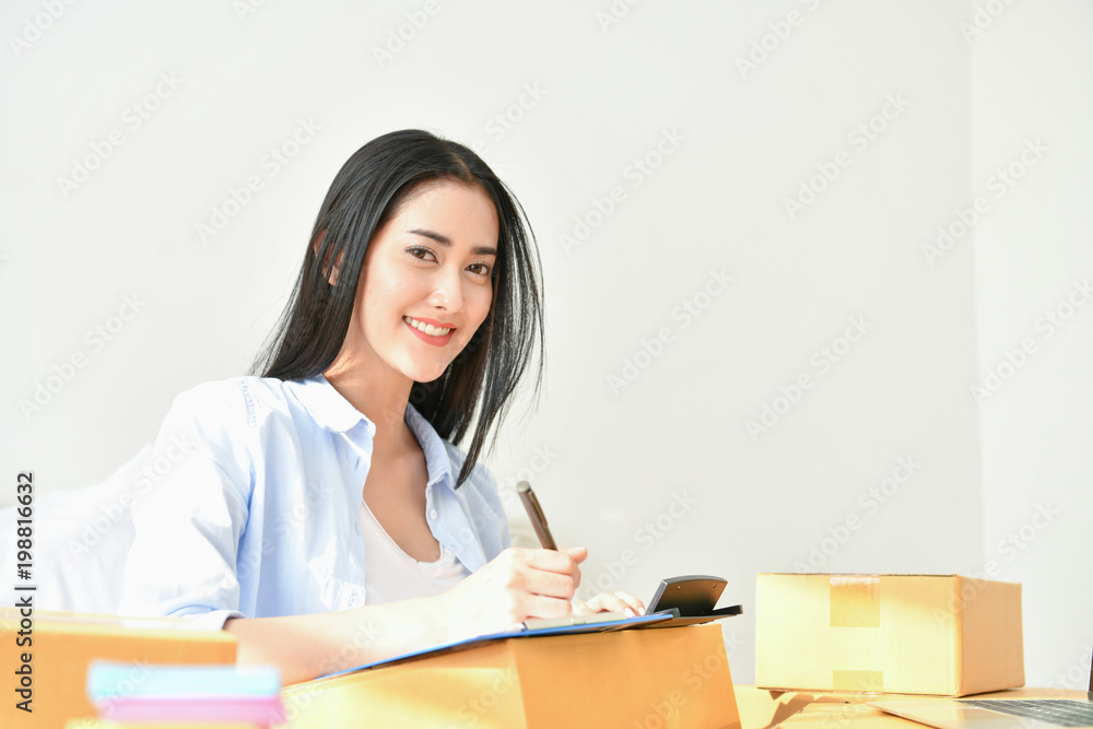 Sme business concept. Young people are packing their packages.Delivery business Small and Medium Enterprise (SMEs). Young woman is working in the house.Young Owner Start up for Business Online. Sme business concept. Young people are packing their packages.Delivery business Small and Medium Enterprise (SMEs). Young woman is working in the house.Young Owner Start up for Business Online.