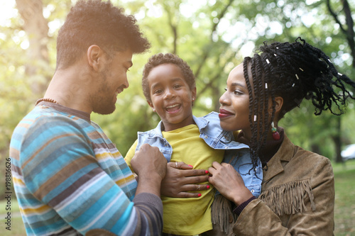  Portrait of cheerful African American parents with daughter in park.