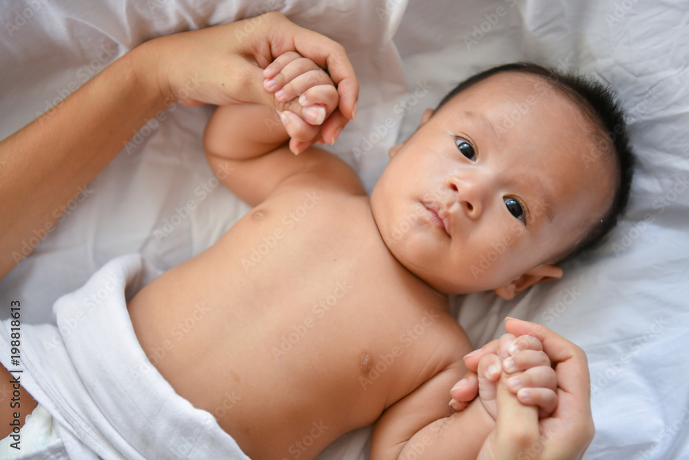 Newborn Concept. Mother and child on a white bed. Mom and baby boy playing in bedroom. Parent and little kid relaxing at home. Family having fun together. Newborn baby is fussing and crying. Newborn Concept. Mother and child on a white bed. Mom and baby boy playing in bedroom. Parent and little kid relaxing at home. Family having fun together. Newborn baby is fussing and crying.