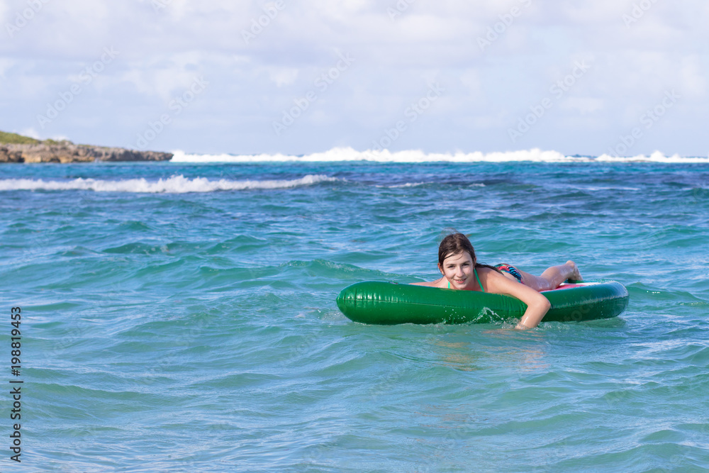 Beautiful teenage girl having fun at the beach with an inflatable toy in the Caribbean sea. Freedom or vacations concept Beautiful teenage girl having fun at the beach with an inflatable toy in the Caribbean sea. Freedom or vacations concept