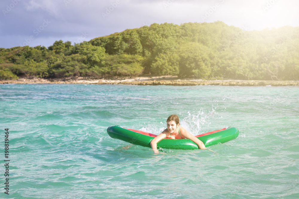Beautiful teenage girl having fun at the beach with an inflatable toy in the Caribbean sea. Freedom or vacations concept