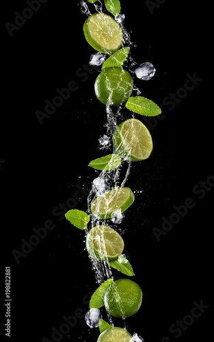 Slices of lime falling in water splash on black background