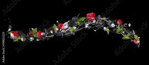 Mix of berry fruit in water splash, isolated on black background