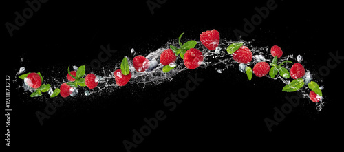 Raspberries falling in water splash on black background