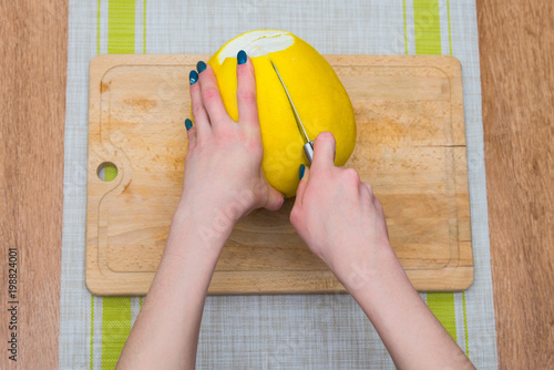 Girl cleans a pomelo on a wooden board photo