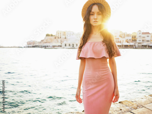 Stylish brunette woman enjoying sunrise on seafront