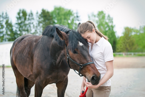 Brown horse together with her favorite owner young teenage girl