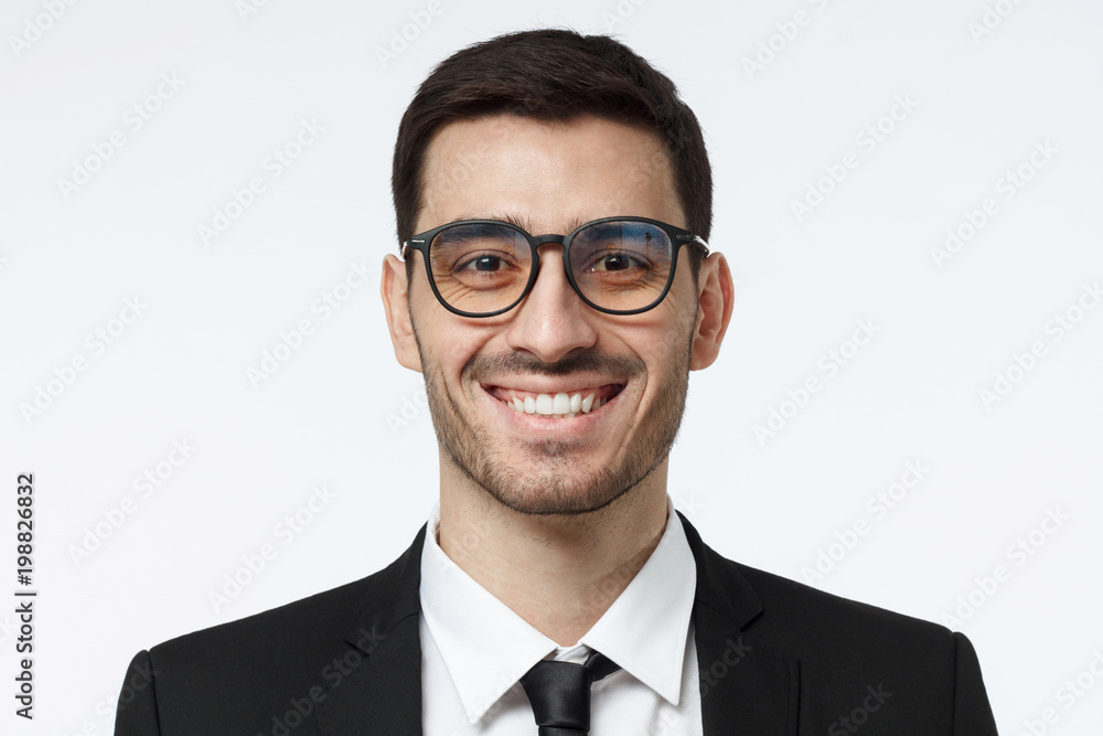 Horizontal headshot of handsome business man pictured isolated on grey background with stylish eyeglasses on, showing happy friendly smile as if willing to share his newest ideas Horizontal headshot of handsome business man pictured isolated on grey background with stylish eyeglasses on, showing happy friendly smile as if willing to share his newest ideas