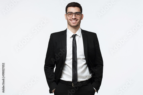 Картината върху платно Portrait of a cheerful business man dressed in black suit, posing  standing with