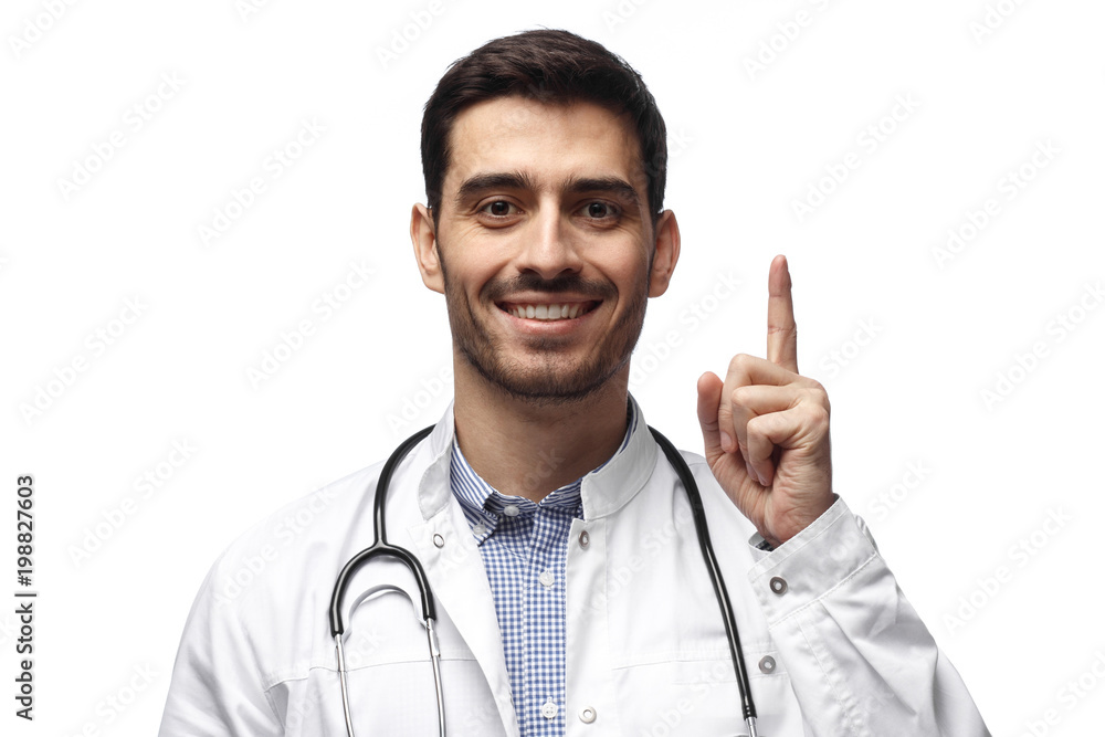 Attractive young man doctor pointing up with his finger isolated on white background Attractive young man doctor pointing up with his finger isolated on white background