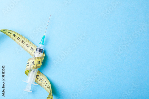 Syringe with a needle and yellow measuring tape. Injections for body beauty and weight loss. Drug for muscle growth of bodybuilders photo