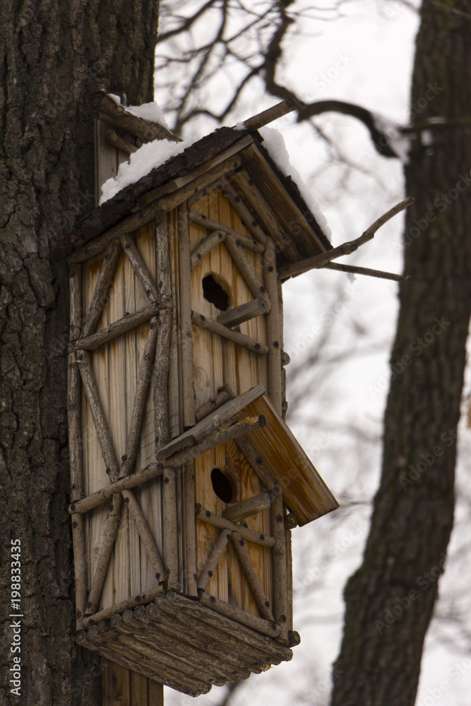 Double decker wooden birdhouse hanging on a tree background