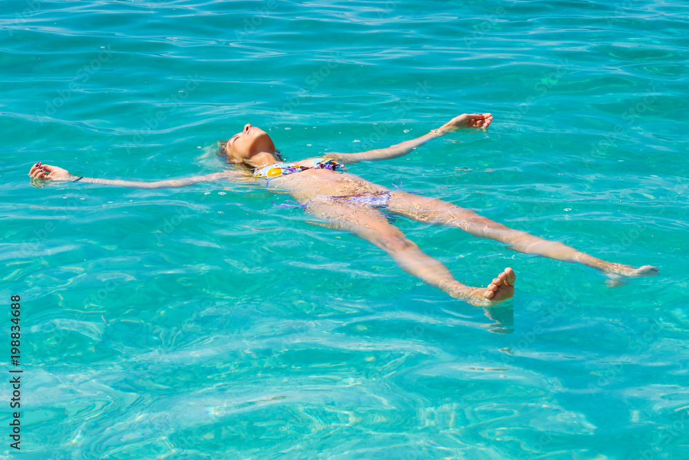 Beautiful girl swimming on back in the blue  sea