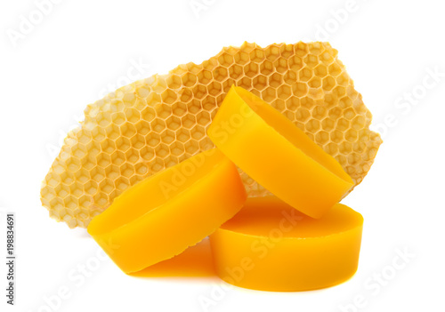 Yellow natural bee wax with a piece of honey cell on a white background.