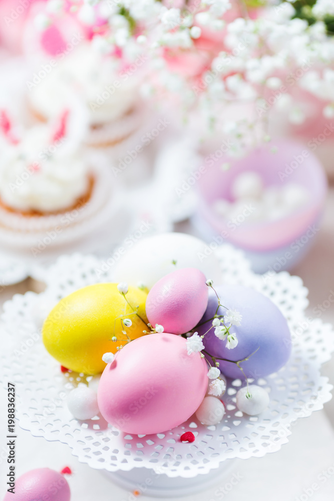 Easter eggs in pastel color on a white cake stand, bunny cupcakes and flowers. Festive light background Easter eggs in pastel color on a white cake stand, bunny cupcakes and flowers. Festive light background